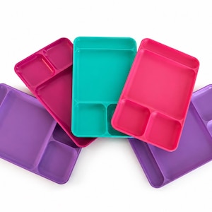 May include: A collection of five rectangular divided trays in vibrant colors including magenta, teal, hot pink, and purple. Each tray features a large main compartment and two smaller side compartments, arranged in a fan-like overlapping display.