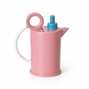 May include: A cylindrical ceramic teapot in a dusty rose pink finish. It features a white curved handle topped with a circular loop, a small triangular spout, and a bright blue cylindrical lid knob centered on the flat top surface of the vessel.