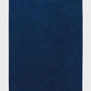 May include: A rectangular textile piece in a solid, deep navy blue color. The fabric features a consistent, soft-textured surface with a subtle matte finish. A small, dark rectangular tag is visible on the bottom right edge of the item.