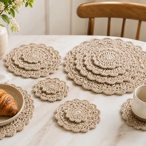 May include: A collection of round, beige crochet doilies and placemats featuring intricate, scalloped edges and detailed circular patterns. These handmade textile items are arranged in various sizes, including small coasters and larger circular mats.