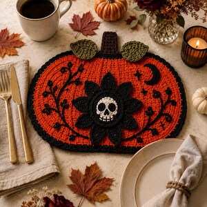 Può includere: Una tovaglietta all'uncinetto a forma di zucca in arancione vivace con bordo nero. Il centro presenta un motivo floreale nero con un teschio bianco. Intricati ricami di viticci neri, una luna crescente e piccole stelle decorano la superficie.