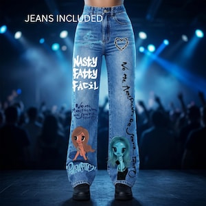 Könnte beinhalten: Hellblaue Jeans mit hoher Taille, verziert mit dem weißen Schriftzug "NASTY FATTY FACIL", einem Herz aus Stacheldraht und zwei Cartoon-Figuren. Die Hosenbeine sind mit schwarzer Handschrift und blauen Graffiti-Elementen bedruckt.