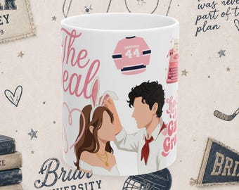 Könnte beinhalten: Ein weißer Keramikbecher mit einer farbenfrohen Illustration von zwei Figuren, eine davon mit Hasenohren, neben einer rosa Schreibmaschine, einem rosa Eishockeytrikot mit dem Text GRAHAM 44 und dem rosa Schriftzug The Real sowie einer roten Krawatte.