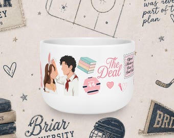 Könnte beinhalten: Ein weißer Keramikbecher mit einer farbenfrohen Illustration eines Paares, einem Bücherstapel, einem rosa Eishockeytrikot mit der Nummer 44, einem Mikrofon und dem Text The Deal. Das Design enthält eine rosa Briefmarkengrafik mit der Aufschrift Official Member of Briar U Book Club.