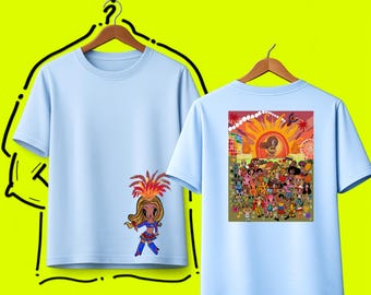 Könnte beinhalten: Ein hellblaues T-Shirt mit einer kleinen Zeichentrickfigur mit Federschmuck auf der Vorderseite und einer großen, bunten Grafik auf der Rückseite, die eine Menschenmenge bei einem Festival unter einer hellen Sonne zeigt. Der Text DESIGN #1 ist sichtbar.