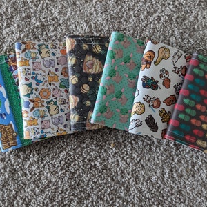 May include: Eight different colorful fabric wallets with various patterns, including a pineapple design, a Star Wars design, a Baby Yoda design, a bee design, a Pokemon design, and an Animal Crossing design.