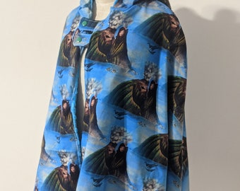 May include: A blue hooded cape with a repeating pattern of volcanoes erupting. The cape has green buttons on the front.