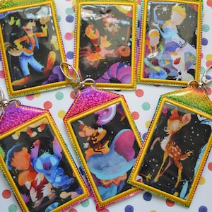 Peut inclure: Cinq porte-clés colorés avec différents motifs de personnages Disney. Chaque porte-clés est doté d'un insert en plastique transparent avec une image colorée d'un personnage sur fond noir. Les porte-clés sont en tissu pailleté et ont une bordure dorée.
