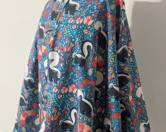 May include: A hooded blue and white cape with a floral and skunk print. The cape has a yellow trim and is made of a soft, comfortable fabric.