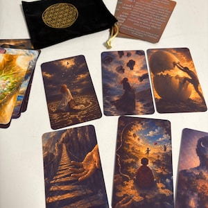 May include: A black velvet drawstring pouch with a gold flower of life symbol, accompanied by a set of rectangular oracle cards featuring surreal, dreamlike illustrations of figures in landscapes, and an instruction card with printed text.