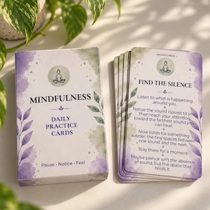 May include: A deck of mindfulness daily practice cards featuring a box and individual cards with purple and green watercolor accents. The text reads Mindfulness Daily Practice Cards, Pause, Notice, Feel, and Find the Silence with instructions.