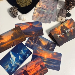 Può includere: Un mazzo di carte metaforiche associative Place of Power con illustrazioni paesaggistiche di vulcani, tramonti, oceani e mulini a vento. Il set include un sacchetto di velluto nero con un simbolo dorato del fiore della vita, pigne e piccole pietre.