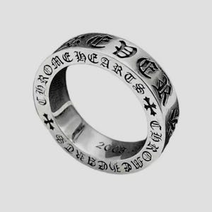 K&ouml;nnte beinhalten: Ein silberfarbener Metallring mit der eingravierten Aufschrift CHROME HEARTS in einer gotischen Schriftart auf dem &auml;u&szlig;eren Band. Das Design enth&auml;lt kleine Kreuzsymbole zwischen den Buchstaben und die Jahreszahl 2003 auf der Innenseite.