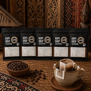 Puede incluir: Cinco bolsas de café de goteo negras etiquetadas como Kopi Drip con varios orígenes de Arábica, incluidos Gayo, Mandheling, Toraja Kalosi, Flores Bajawa y Papua Wamena. Se incluyen un cuenco de madera con granos de café y una taza de cerámica.