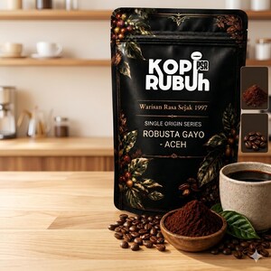 Puede incluir: Una bolsa de café negra etiquetada como KOPI RUBUH con el texto Warisan Rasa Sejak 1997, Single Origin Series y Robusta Gayo - Aceh. La bolsa presenta ilustraciones de granos y hojas de café, junto a un cuenco de madera con café molido.