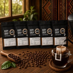 Könnte beinhalten: Fünf schwarze Beutel Kopi Drip Kaffee mit den Etiketten Lampung, Toraja, Ijen, Pagaralam und Dampit Robusta. Ein Holzlöffel enthält geröstete Kaffeebohnen neben einer Glastasse mit einem Kaffeefilterbeutel, der mit heißem Wasser gefüllt wird.