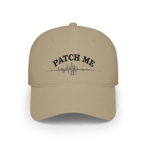 May include: A tan baseball cap featuring the black text PATCH ME printed in an arched font above a black graphic of a jagged heartbeat line and the word GLITCH printed in small black letters directly underneath the center of the line.