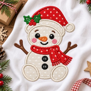 May include: A white fabric towel featuring an embroidered snowman with a red polka dot hat and scarf, an orange carrot nose, black button eyes, two black buttons on the torso, and brown stick arms, accented with green holly and red berries.