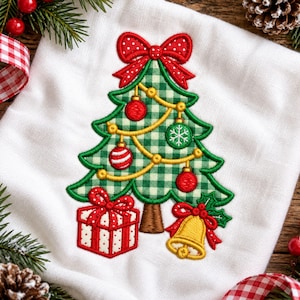 Könnte beinhalten: Ein weißes Stofftuch mit einer Stickerei eines grün-weiß karierten Weihnachtsbaums. Der Baum ist mit einer roten Schleife, gelber Girlande sowie roten und grünen Kugeln verziert. Am Fuß befinden sich ein rot-weißes Geschenk und eine gelbe Glocke.