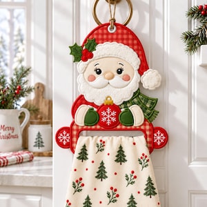 May include: A hanging kitchen towel holder featuring a plush Santa Claus figure with a red and white checkered hat, a green scarf, and green mittens holding a red ornament. The attached cream-colored towel is decorated with a pattern of green pine trees and red berries.