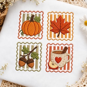May include: A white fabric square featuring four embroidered scalloped-edge patches. The designs include an orange pumpkin, a red maple leaf, two brown acorns on a branch, and a beige mug with a red heart, a cinnamon stick, and an apple slice.