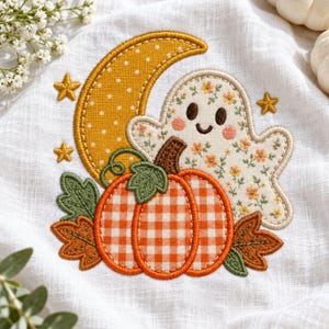 May include: An embroidered patch on white fabric featuring a yellow crescent moon with white dots, a ghost with a floral pattern, and an orange and white gingham pumpkin. The design includes green leaves, brown stems, and three small yellow stars.
