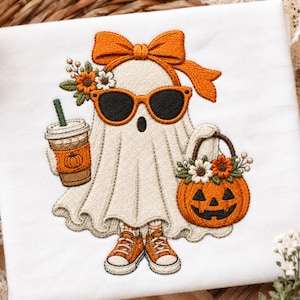 May include: An embroidered design on white fabric featuring a ghost wearing orange sunglasses and a large orange bow. The ghost holds a coffee cup with a pumpkin icon and a jack-o'-lantern bucket filled with flowers, while wearing orange sneakers.