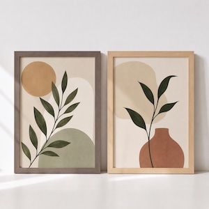 May include: Two framed wall art prints featuring botanical illustrations. The left print shows a leafy branch against a tan circle and sage green shape. The right print displays a leafy branch in a terracotta vase against a beige background.