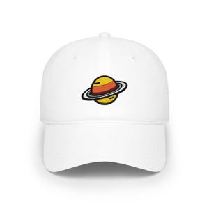 May include: A white baseball cap featuring an embroidered graphic of a planet with yellow and orange horizontal bands and a dark grey ring encircling the centre. The cap has a structured crown, a curved brim, and a button on the top centre.