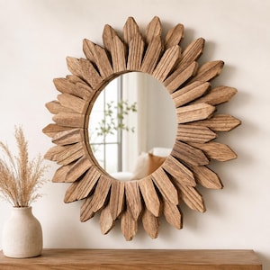 May include: A circular wall mirror featuring a sunburst frame constructed from numerous pointed, light brown wooden slats arranged in a layered, radiating pattern. The mirror has a smooth, reflective center surface with visible wood grain texture.