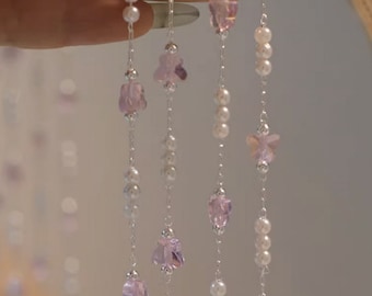 May include: A delicate necklace with multiple strands of silver chain and small white beads. Each strand features a variety of light purple crystal charms in different shapes.