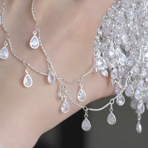 May include: A silver necklace with multiple strands and teardrop-shaped crystal accents.