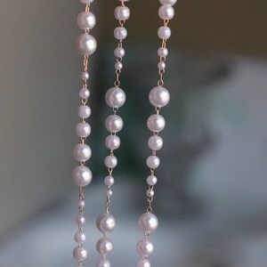 Peut inclure: Trois rangs de collier de perles avec une chaîne en or. Les perles sont blanches et rondes.