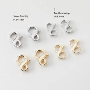 May include: Two silver and two gold lobster clasps. The silver clasps are 13 by 8.5 mm and have a double opening. The gold clasps are 14.6 by 11 mm and have a single opening.