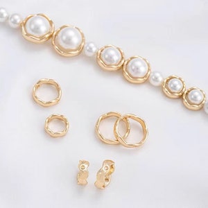 Puede incluir: Un conjunto de joyas doradas que incluye un collar de perlas con una cadena delicada y varios pendientes de aro de diferentes tamaños.