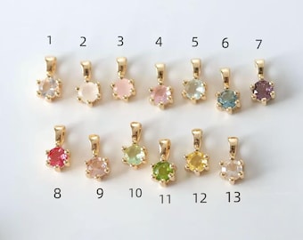 May include: Thirteen gold-toned pendants, each featuring a single round faceted gemstone in various colors. The pendants are arranged in two rows and numbered 1 through 13. Each piece has a small gold bail at the top for attachment to a chain.