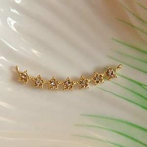 May include: Gold-toned star-shaped charm with clear rhinestones. The charm is designed to be used as a jewelry component.