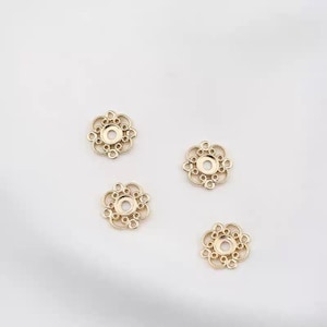 Puede incluir: Cuatro componentes de joyer&iacute;a dorados en forma de flor de filigrana. Cada componente tiene un agujero central rodeado por un dise&ntilde;o calado decorativo con peque&ntilde;os c&iacute;rculos. Los componentes est&aacute;n dispuestos sobre un fondo blanco.