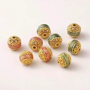 Peut inclure: Perles dorées en filigrane avec des accents d'émail rouge et vert. Les perles sphériques présentent des motifs ajourés complexes. Idéales pour la création de bijoux et les projets d'artisanat.