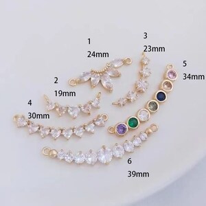 Peut inclure: Six apprêts de bijoux dorés, chacun avec un design différent et orné de cristaux clairs et colorés. Les mesures sont en millimètres, la pièce la plus longue mesurant 3,9 cm.