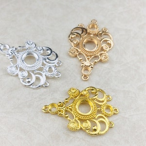 Könnte beinhalten: Drei verzierte Metall-Anhänger mit filigranem Design. Die Anhänger sind in Silber, Gold und Gold mit dunklerer Oberfläche. Jeder Anhänger hat eine kreisförmige Öffnung in der Mitte.