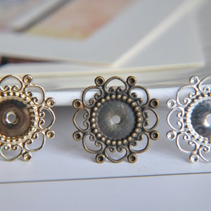 May include: Three decorative metal embellishments with intricate filigree designs. The embellishments are in gold, bronze, and silver.