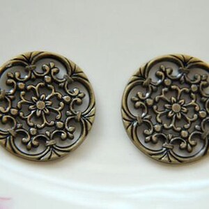 May include: Two antique gold-toned metal buttons with a decorative floral design.