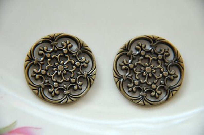 May include: Two antique gold-toned metal buttons with a decorative floral design.