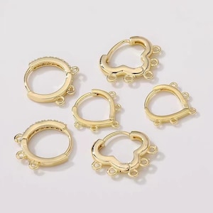 May include: Six gold-toned earring findings with multiple jump rings. The findings are in the shapes of a circle, a heart, and a cloud.