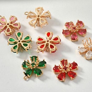 May include: Assortment of gold-tone flower-shaped charms with various colored crystal accents. The charms have a hole in the center for attaching to jewelry or other crafts.