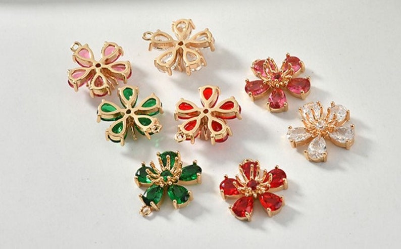 May include: Assortment of gold-tone flower-shaped charms with various colored crystal accents. The charms have a hole in the center for attaching to jewelry or other crafts.
