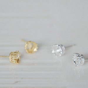 Könnte beinhalten: Drei Paar Ohrring-Fassungen, zwei goldfarben und eine silberfarben, mit einem kronenförmigen Design. Die Fassungen sind so konzipiert, dass sie einen Stein oder einen anderen Schmuckstein aufnehmen können.