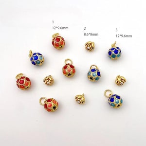 May include: Assortment of enamel charms in various colors, including red, blue, and turquoise. The charms are shaped like spheres with a decorative pattern and are approximately 12 mm in diameter. The charms are attached to gold-colored loops.