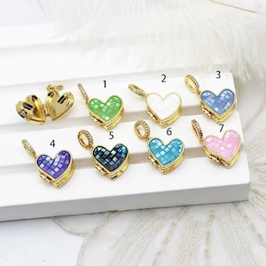 May include: Seven gold heart-shaped locket charms with different colored mosaic designs. The lockets are open and have a small hinge on the side. The colors of the lockets are green, white, blue, purple, blue and green, turquoise, and pink.